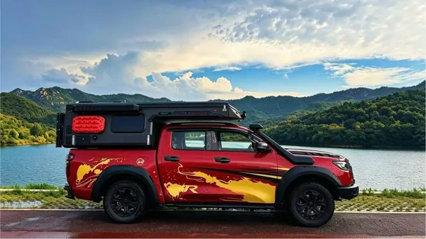 Red pickup with a slide-in camper by a mountain lake