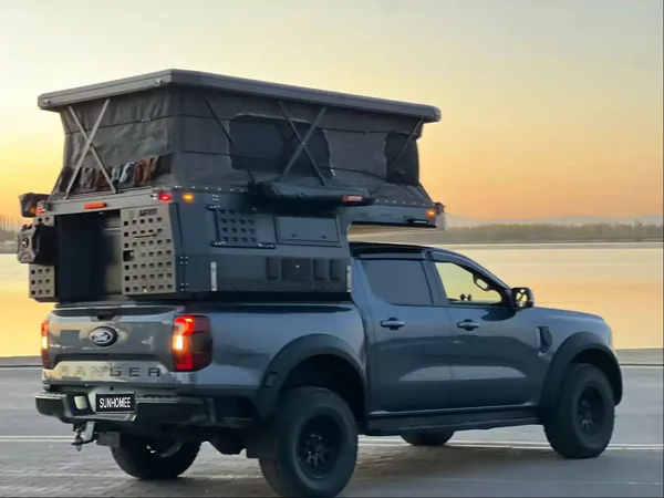 Ford Ranger with the slide-on camper roof raised at sunset by the sea