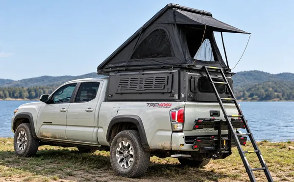Integrated pop-up topper with the hard-shell tent open on a white Toyota Tacoma by a lake