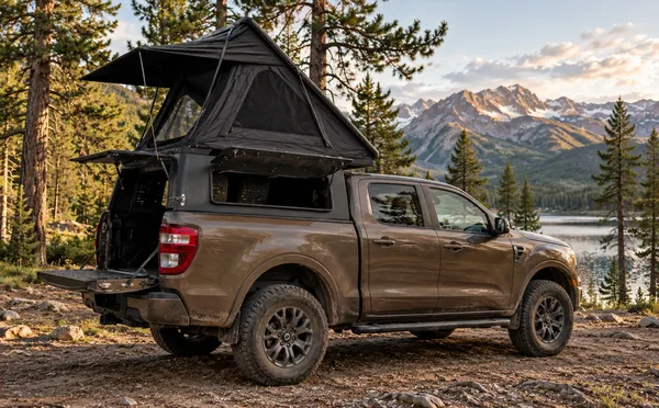 Integrated pop-up canopy on a brown ute in the mountains, side door open