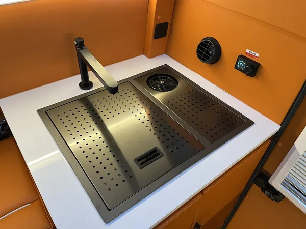 Stainless sink with folding faucet on a white worktop