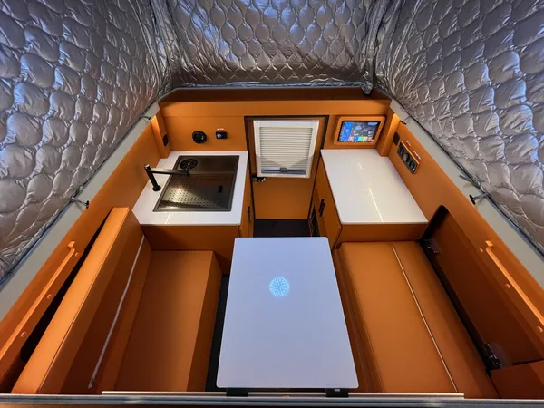 Orange camper interior with table, sink and fridge, top view