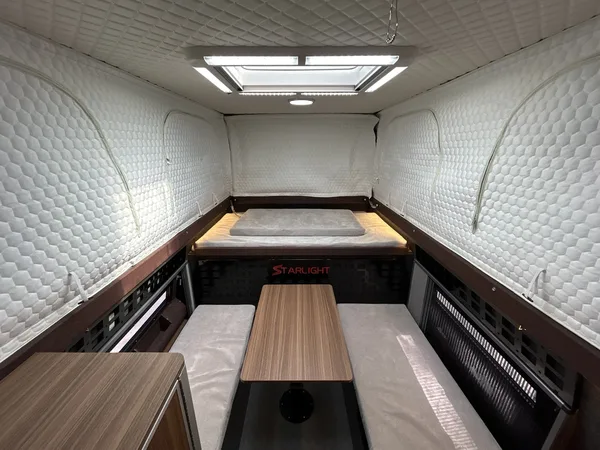 Wood and grey camper interior with dinette table and roof hatch