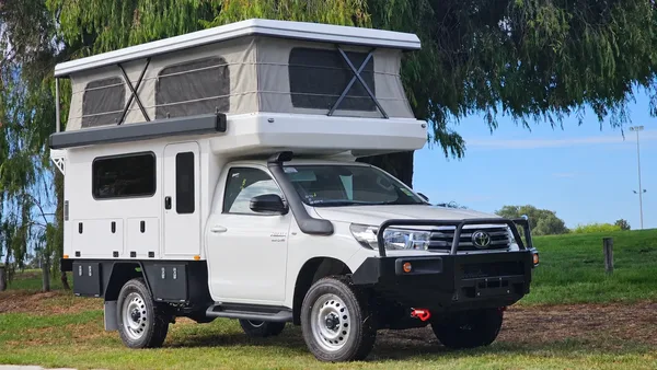 Toyota Hilux with a white SUNHOMEE tray-mount camper, roof raised