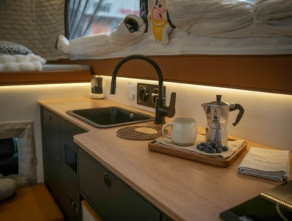 Camper sink with black faucet and wood worktop