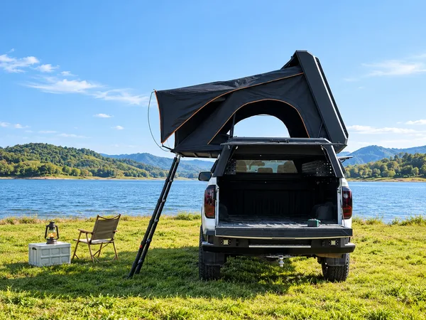 Stealth pop-up canopy open on the grass by a lake, rear view