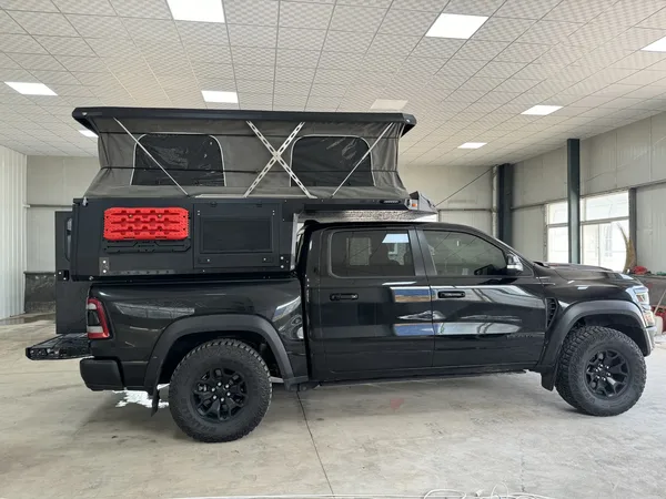 Black RAM pickup with a SUNHOMEE slide-in camper, roof raised