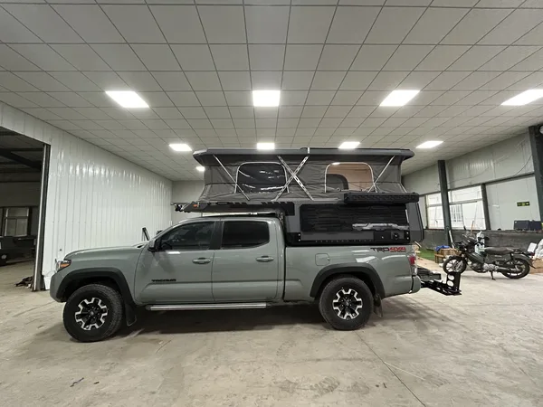 Toyota Tacoma with a SUNHOMEE slide-in camper, roof raised
